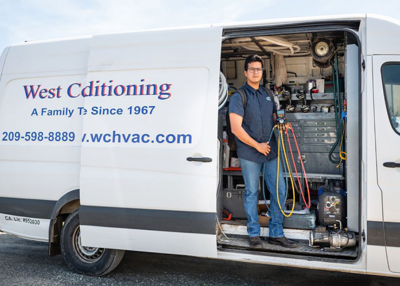 HVAC contractor from West Coast Air Conditioning posing in van with equipment