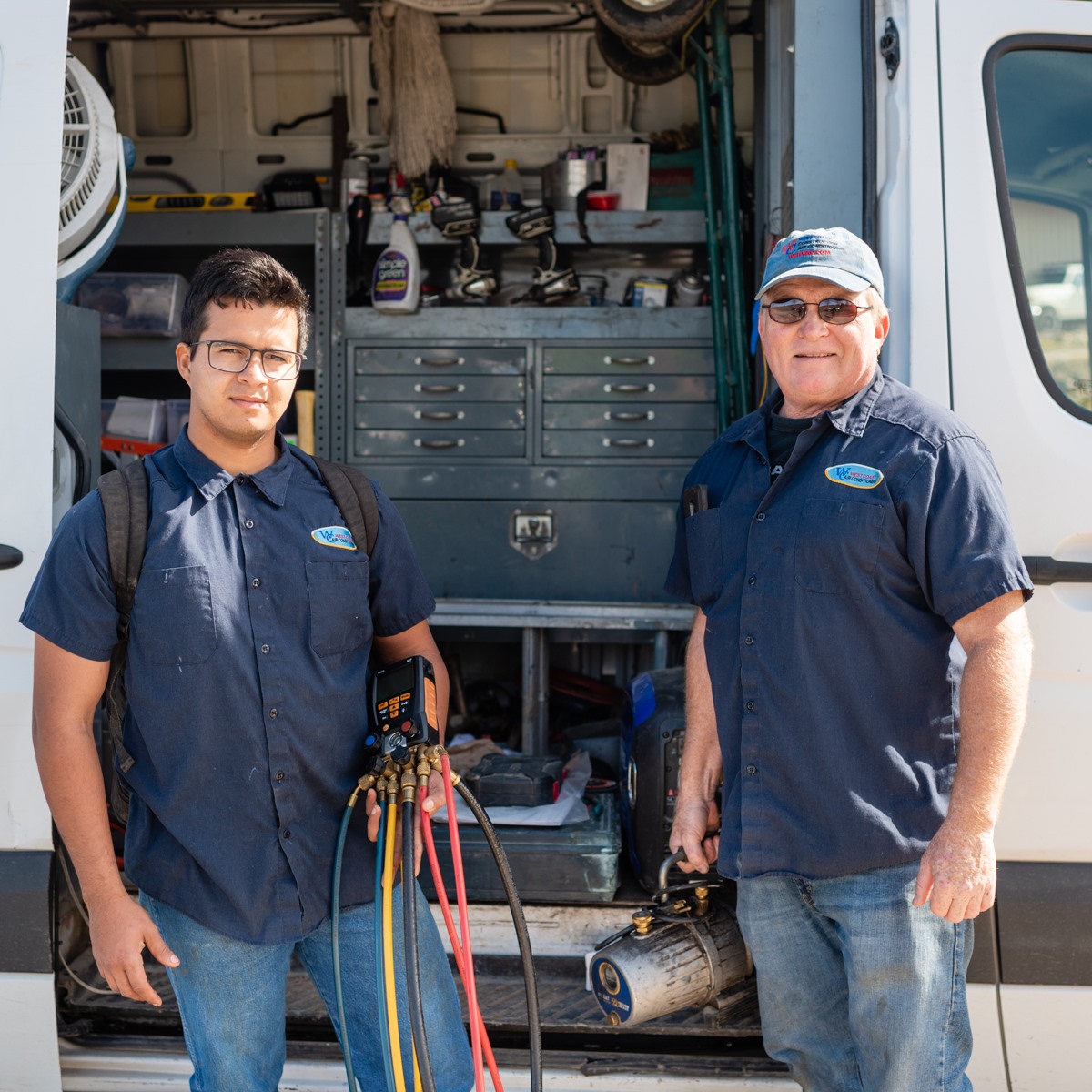 Two HVAC repair contractors posing with work van