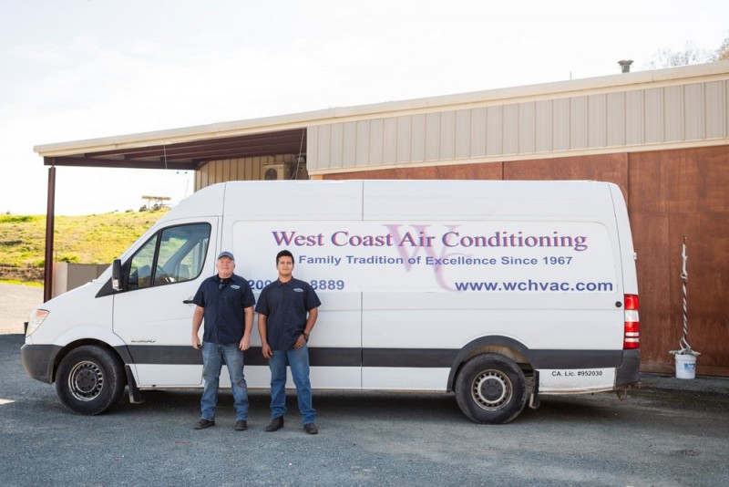 Two HVAC technicians posing with the West Coast Air Conditioning van
